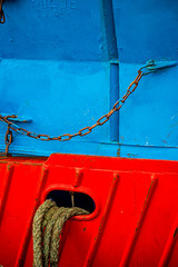 Mooring line of a trawler on a red ship hull