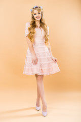 beautiful woman in delicate lacy dress and colorful floral wreath on yellow background