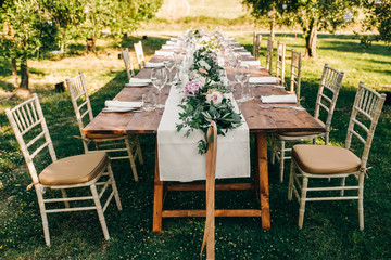 Floral garland of eucalyptus and pink flowers lies on the table for wedding reception. Italian...