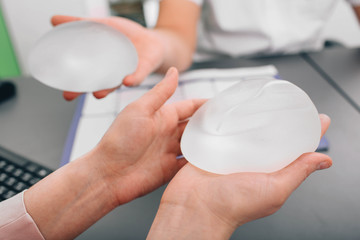 Young woman consultation and selection of breast silicone implants. breast augmentation