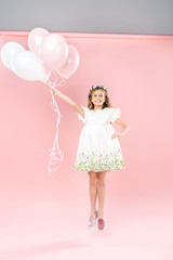 carefree child jumping with white and pink air balloons on bicolor background
