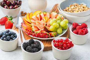 Raw vegan gluten and grain free paleo granola or muesli made from nuts. Fruit berries platter, strawberries blueberries raspberries peach figs red currant, almond milk side view, selective focus