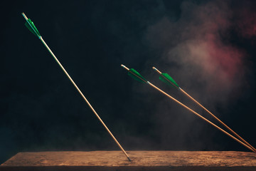 Three wood arrow on a wooden table. Beautiful  smog background. Medieval weapons are handmade.