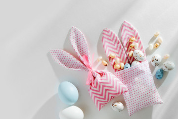 Easter Bunny bags with treats, candy, chocolate eggs on white background. Happy Easter concept.