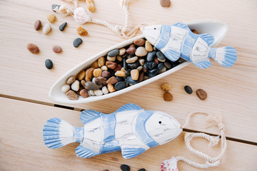 Decorative fish with sea pebbles  on a  wooden background. Nautical concept.