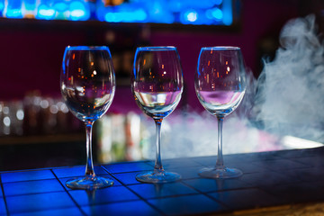 Two empty wine glasses arranged on the counter before the party to start in restaurant or bar with smoke 