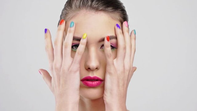 Beautiful woman with bright vivid makeup. Sexy adult girl with colorful nails on the hands.