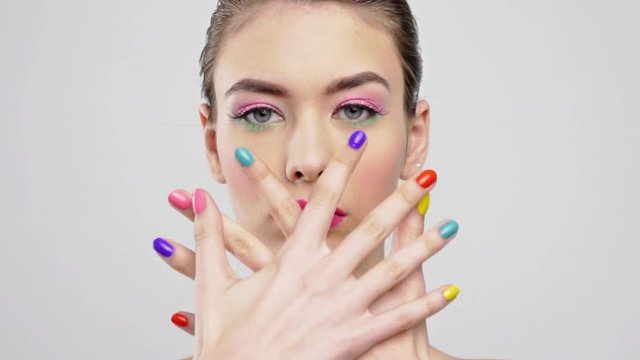 Beautiful woman with bright vivid makeup. Sexy adult girl with colorful nails on the hands.