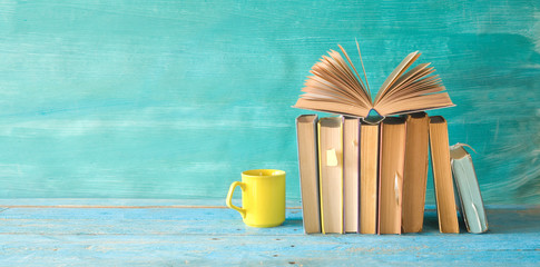 Open book on a row of old books and a cup of coffee. Reading, learning, education, literature,...
