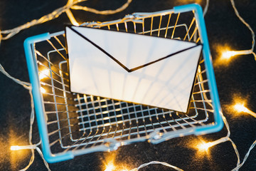 shopping cart with email envelope on concrete desk surrounded by fairy lights