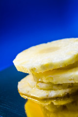 Blue monophonic background. The fresh cut pineapple on round segments. Green leaves. Tropical fruit. Vitamins and health.
