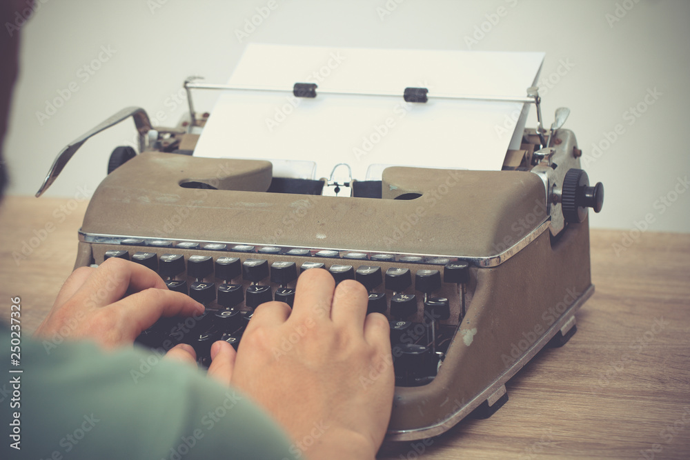 Fototapete hands writing on old typewriter on desk..retro typewriter on wooden table..writer hands typing typew