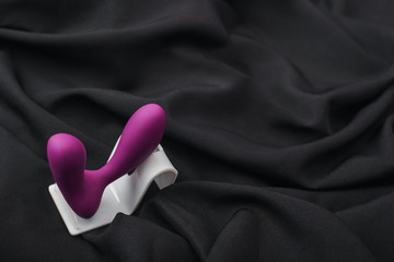 Enhance your sex life. Close up of silicone prostate massager on a black silk fabric