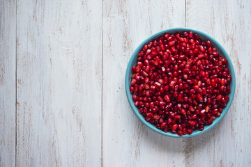 Pomegranate seeds on a white wooden table. 