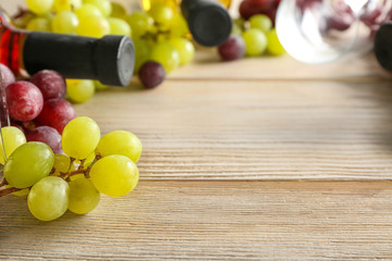 Bottles of wine with fresh grapes on wooden table