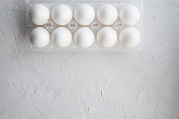 ten white chicken eggs in a plastic container. Copy space. top view