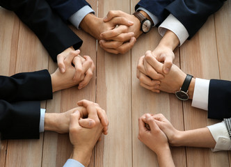 Group of people praying before meeting in office