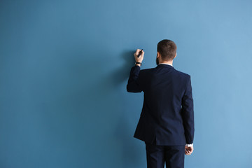Man in formal clothes writing something on color wall