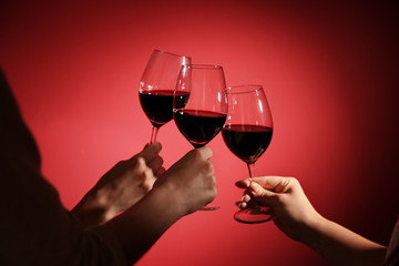 Naklejka na ściany i meble Women clinking glasses with tasty red wine on color background