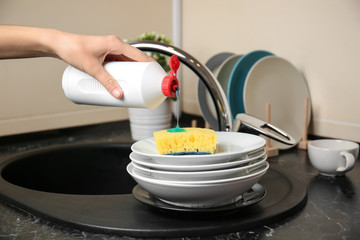 Woman washing dishware in kitchen