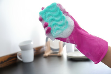 Woman with sponge for washing dishes in kitchen