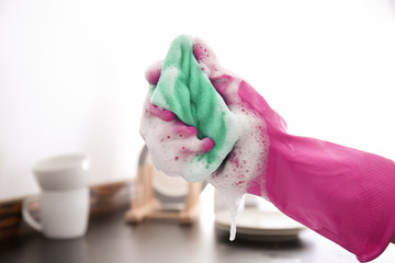 Woman with sponge for washing dishes in kitchen