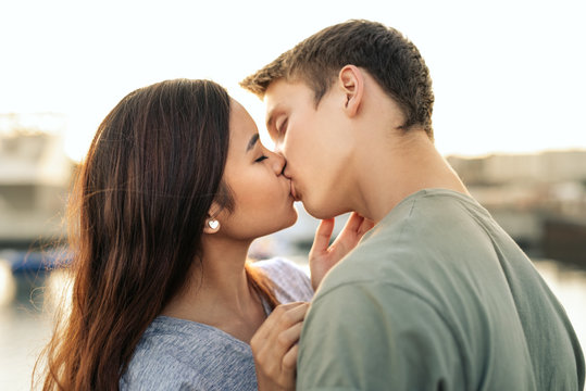 Romantic young couple kissing by a harbor in the afternoon