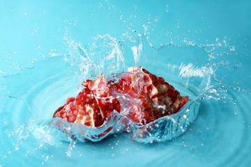 Ripe pomegranate with water splash on color background