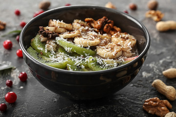 Bowl with tasty oatmeal on grunge background