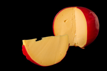 Close up. Head of Dutch cheese Edam and sliced piece. Isolated on black background.