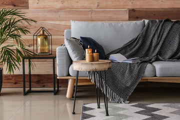 Interior of modern room with sofa and burning candles on table