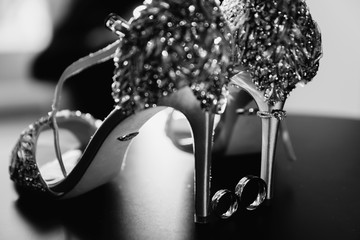 Wedding accessories. Delicate wedding and engagement rings on bride's sparkling shoes