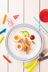 Kid's breakfast - eggs, toasts, cucumber and ketchup