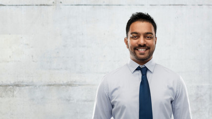 business, office worker and people concept - smiling indian businessman in shirt with tie over gray concrete wall background