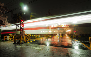 Long exposure of train passing through intersection with flowering Cherry Blossoms
