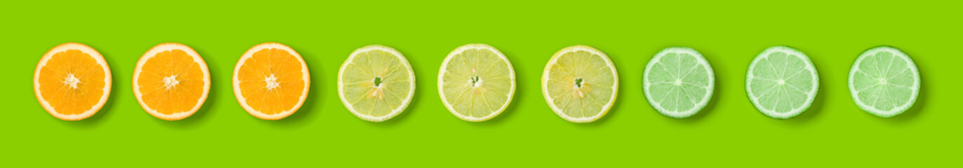 Citrus Fruit pattern on green  background. Orange, Lime, Lemon slices background. Flat lay, top view. Banner, seamless pattern, creative summer food concept..  Pop art design, creative summer concept.