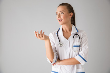 Beautiful young woman cosmetologist doctor isolated over grey wall background.