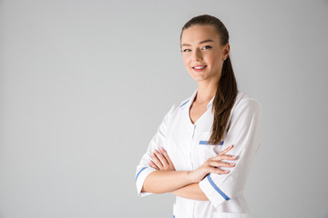 Beautiful young woman cosmetologist doctor isolated over grey wall background.