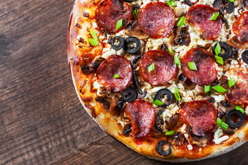 Pizza with Mozzarella cheese, salami, pepper, pepperoni, olives, Spices and mushroom. Italian pizza on wooden table background