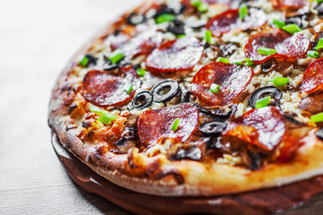Pizza with Mozzarella cheese, salami, pepper, pepperoni, olives, Spices and mushroom. Italian pizza on wooden table background