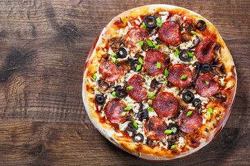 Pizza with Mozzarella cheese, salami, pepper, pepperoni, olives, Spices and mushroom. Italian pizza on wooden table background