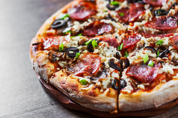 Pizza with Mozzarella cheese, salami, pepper, pepperoni, olives, Spices and mushroom. Italian pizza on wooden table background