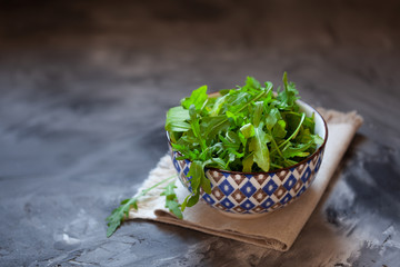 Close up of fresh arugula leaves. Ruccola salad in bowl over dark background