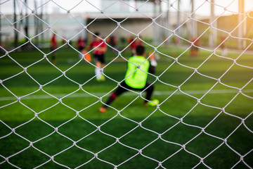 Mesh of goal with blurry of soccer goalkeeper and soccer players