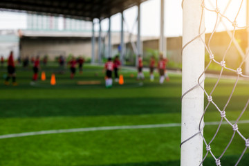 White goalposts and mesh of goal with blurry football players