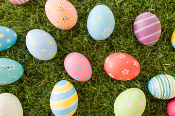 Fototapeta na wymiar easter, holidays and tradition concept - colored eggs on artificial grass