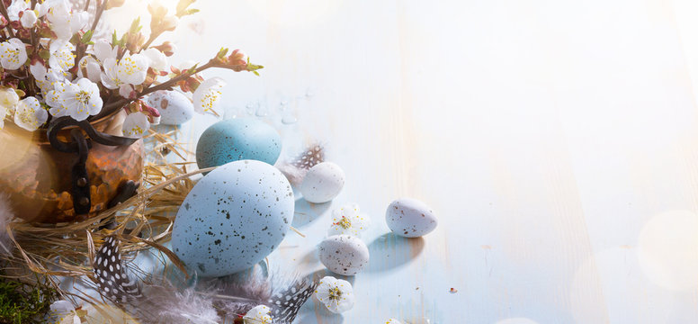 bright Easter background;  Easter eggs basket and sprig flowers on blue table background