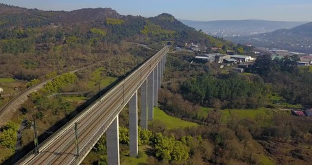 TRAIN BRIDGE IN A GREEN VALLEY WITH FACTORIES, HOUSES AND THE CITY OF OURENSE