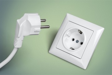 White electrical plug in the electric socket on a wall