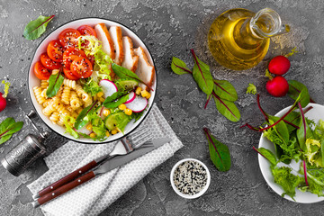 Grilled chicken meat with fresh vegetable salad of tomato, cucumber, radish, lettuce, mangold leaves, corn and pasta for lunch, top view